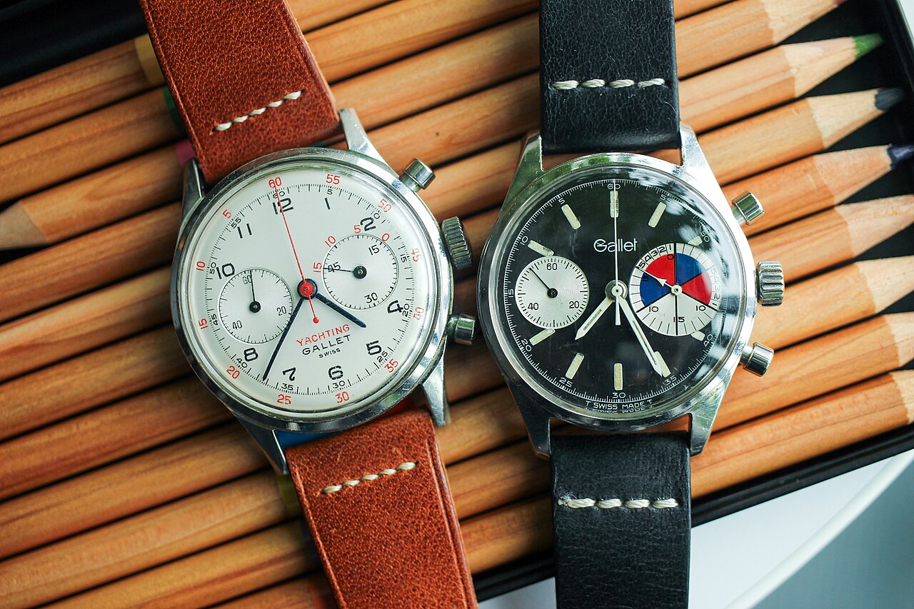 Two vintage Gallet MultiChron chronographs displayed over a case of drawing pencils